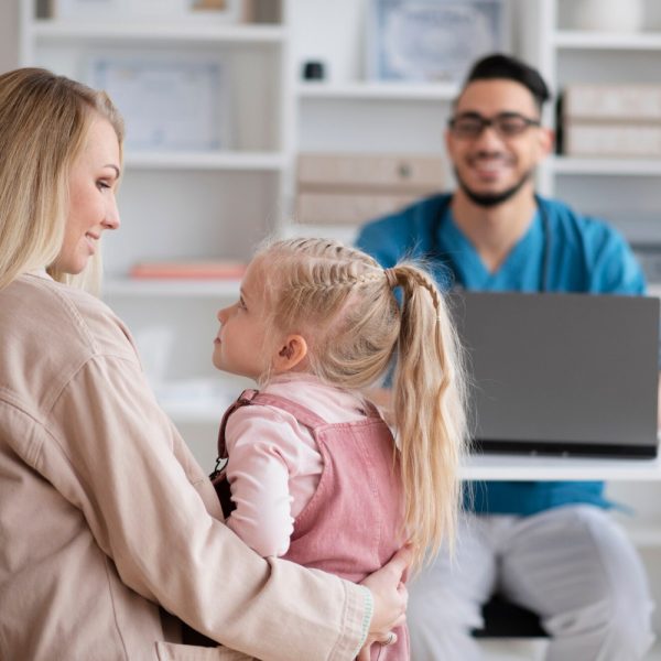 Pediatrician interacting with mother and child, supported by AI Scribe for Pediatrics software.